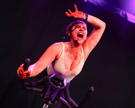 About-to-fall-apart energy … Megan Tomei grimaces and mops her brow during a spin bike workout in SpinQueen™.