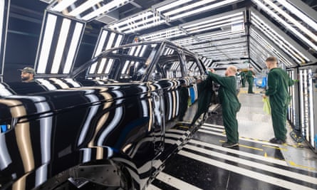 JLR employees check the bodywork on a Range Rover in the paint shop.