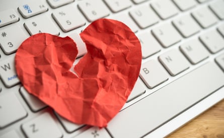 Red broken heart paper on white keyboard computer background.