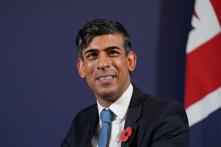 Sunak in front of a UK flag, wearing a poppy