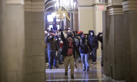 A man holds a flag aloft as he leads a group of demonstrators down the halls of the US Capitol.