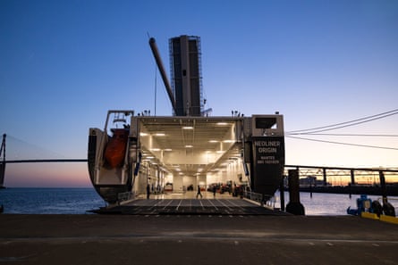 View of the open cargo hold of a ship docked in a harbour at sunrise