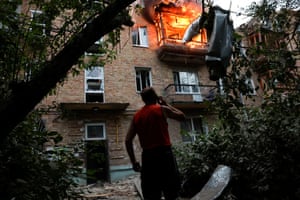 A person stands outside a burning apartment building