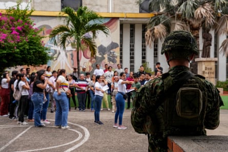 A soldier stands guard at a polling station as women queue to vote