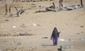 A woman walks across an arid landscape