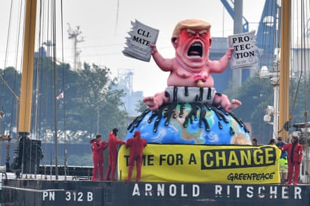 Greenpeace activists protest on a boat with a giant figure featuring US President Donald Trump as a baby, tearing up a climate protection document in Hamburg