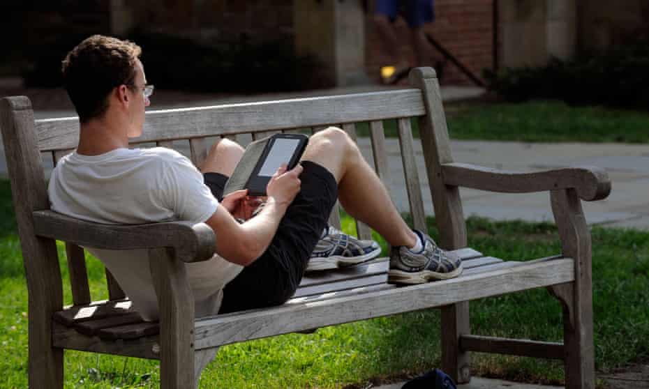 A Yale University Summer School student reading a Kindle sitting in a bench.