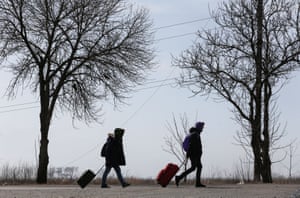 Refugees walk along a road as they leave Mariupol