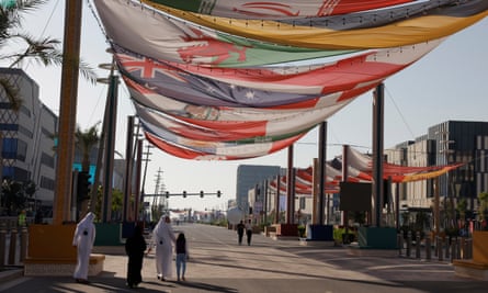 A family walk down the car-free Lusail Boulevard under flags of the competing nations in the Qatar 2022 World Cup.