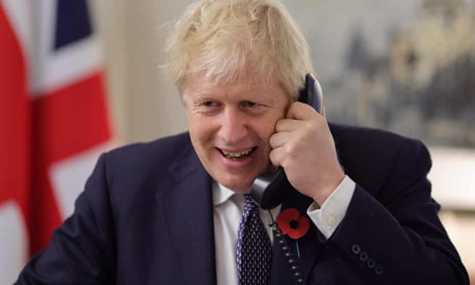 Boris Johnson on phone with UK flag behind him