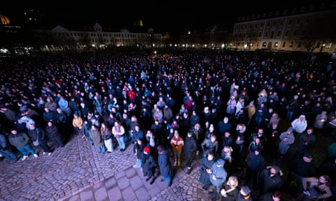 Participants in a silent prayer stand with candles in the Cathedral Square Magdeburg, Germany.