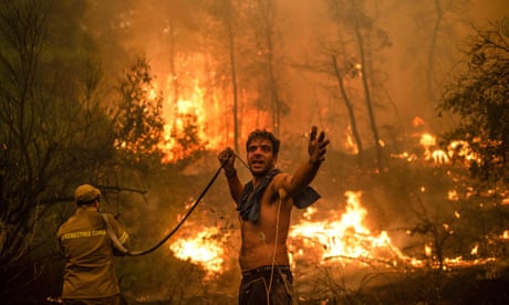 People with hoses attempting to extinguish forest fires approaching the village of Pefki, on Evia island, Greece, in August.