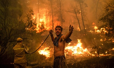 A water hose runs empty for a volunteer fighting forest fires near the village of Pefki on the Greek island of Evia.