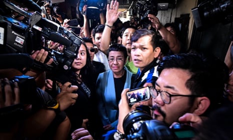 Philippine journalist Maria Ressa (in a blue jacket), surrounded by press and TV journalists
