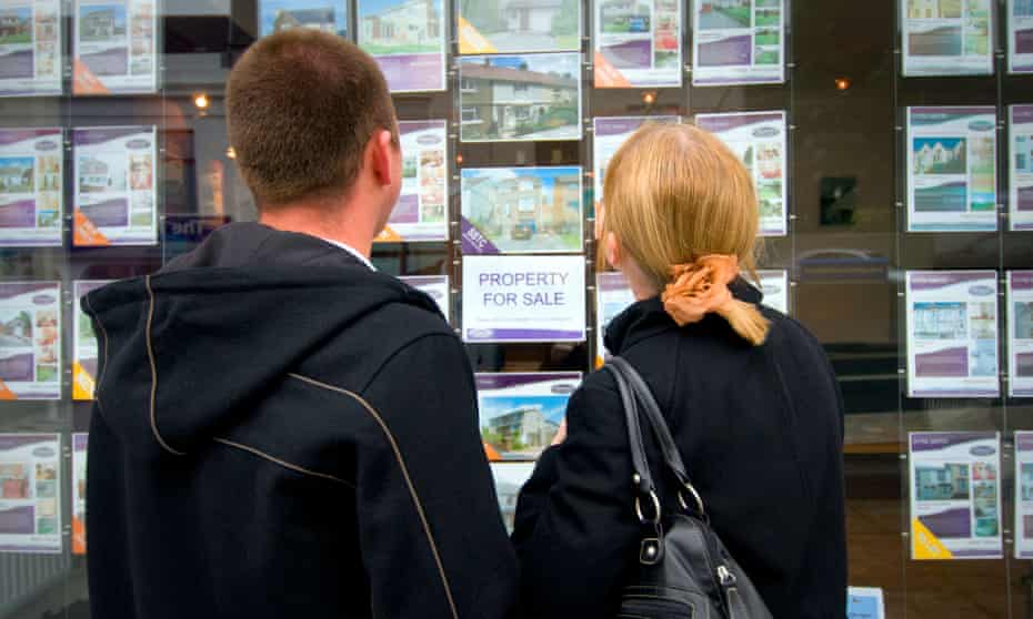 Young couple looking at houses in estate agent's window