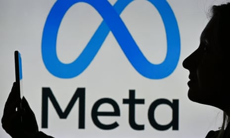 Person holding phone in profile against backdrop of Meta logo