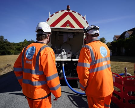 A worker from Thames Water delivering a temporary water supply from a tanker