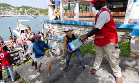 Line of people pass items down steps towards a boat at the shore