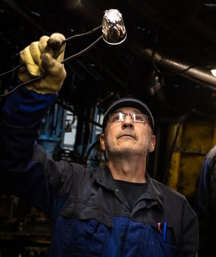 A worker holds a glass up to the light.