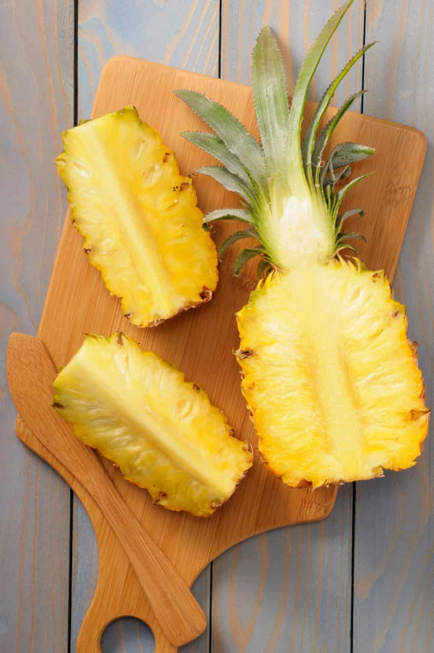 A cut up pineapple on a wooden serving platter.