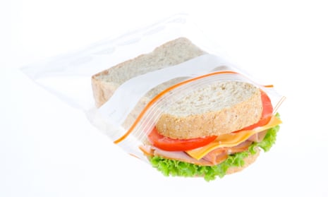 Stock photo on white background of turkey, cheese, tomato and lettuce sandwich halfway in an unbranded plastic baggie.