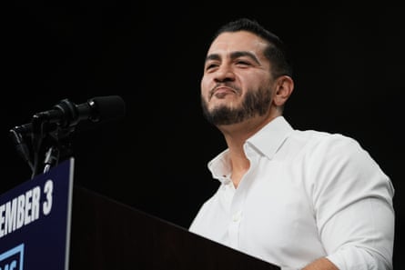 Man in white shirt at lectern on stage.