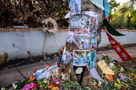Flowers and photographs adorn a makeshift memorial around a tree