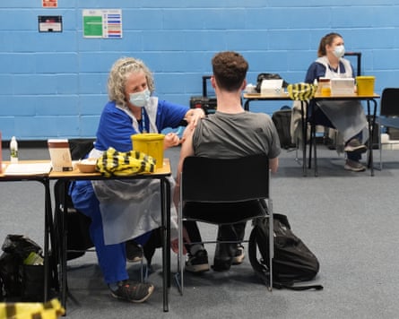 A personification wearing aesculapian cogwheel injecting different personification successful nan arm