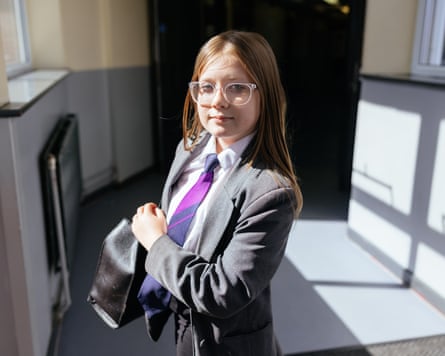 She stands in the corridor, bag on her shoulder