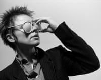 A woman with short hair wearing sunglasses and a black jacket