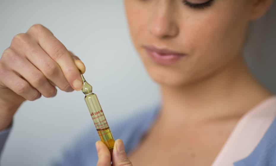 A woman holds a glass ampoule of vitamin D.