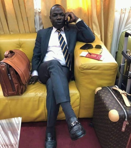 Man in suit sitting on sofa with Louis Vuitton luggage