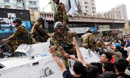 People shake hands with soldiers as they celebrate the resignation of Sheikh Hasina in Dhaka on 5 August.
