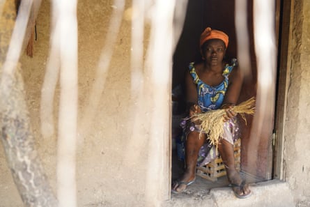 Esperança Correia, from Formosa island, sits inside her home, holding crops