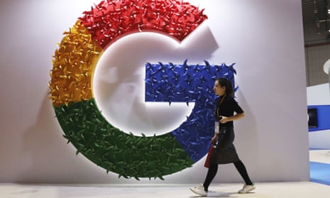 A woman carries a fire extinguisher past the logo for Google at the China International Import Expo in Shanghai earlier this month.