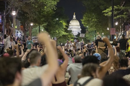 Throngs of people with their fists up walking toward a government building.
