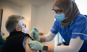 Bridget Connolly receives the first of her two jabs of the Pfizer vaccine from a member of the Newham Health Trust team in London on 7 January