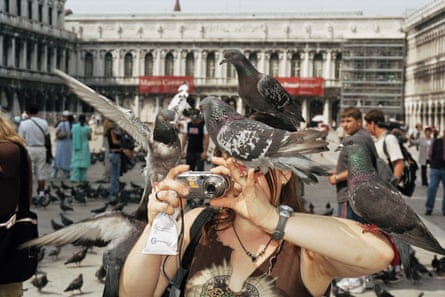 A tourist takes a picture while pigeons surround her in Venice, 2005, by Martin Carr.