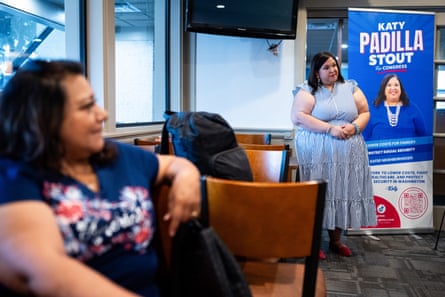 a woman stands in a restaurant as another person watches on