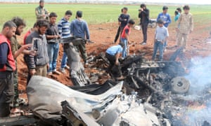 Rebel fighters and civilians gather around the wreckage of a Syrian warplane that was shot down south of Aleppo.