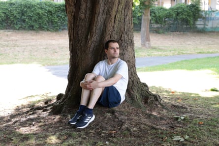 Joe Booth sitting against a tree with his knees drawn up