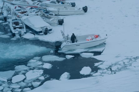 A fisher breaks the ice to enter the port of Nuuk