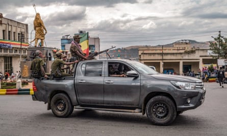 Armed men in combat clothes on the back of a truck driving through a city square