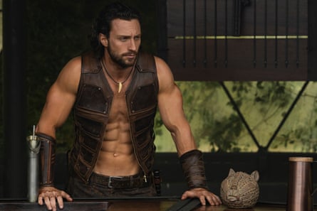 film still of a man wearing a waistcoat over a bare chest looking into the distance