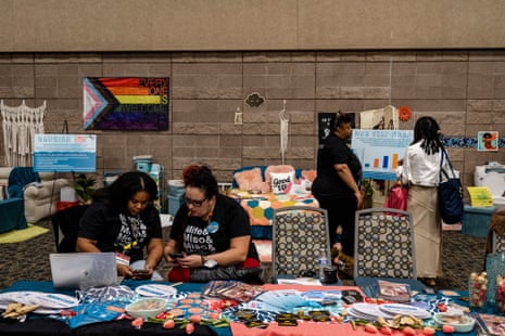 Women sit and stand by a busy reproductive health booth indoor