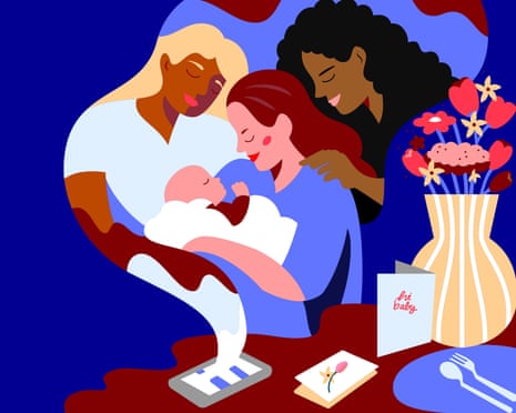 Three adults lean together over a baby, with flowers and baby items nearby.