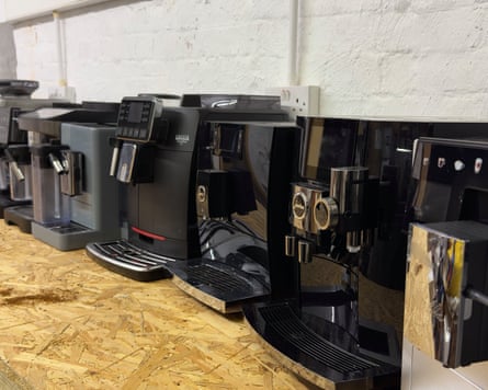 Lineup of seven different bean-to-cup coffee machines on a wooden countertop.