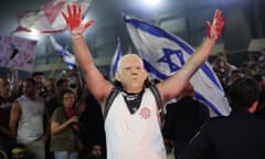 A protester, wearing a mask depicting Israel's Prime Minister Benjamin Netanyahu, raises his hands which are covered in red paint.