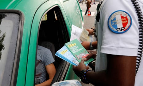 Two police officers give brochures to a motorist explaining the new measures that will ban old cars from Paris. 