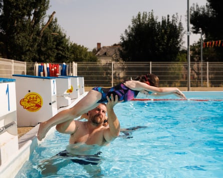 Chris holds daughter as she stretches out in diving position at pool